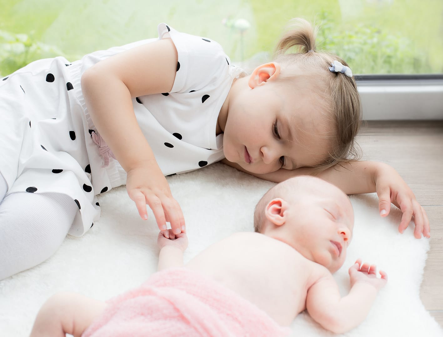 Kleinkind Baby liegend auf weichem Tuch mit Schwesterchen. Schwester berühr das Baby