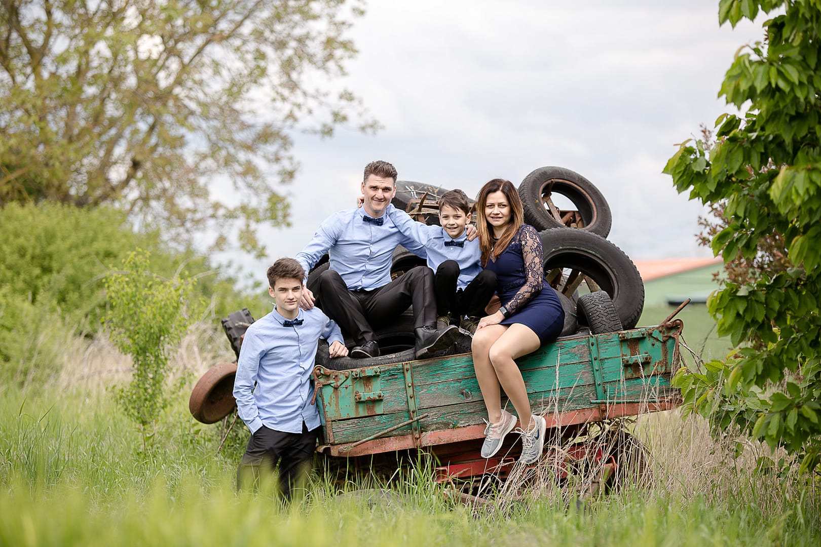 Mama, Papa und zwei Söhne sitzen für eine Familienfoto auf einem alten Traktor im Bauernhof