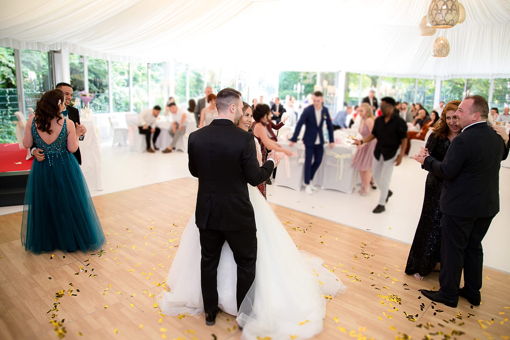 Das Brautpaar tanzt ihren Eröffungstanz mitten auf der Tanzfläche. Auch Gäste tanzen mit.