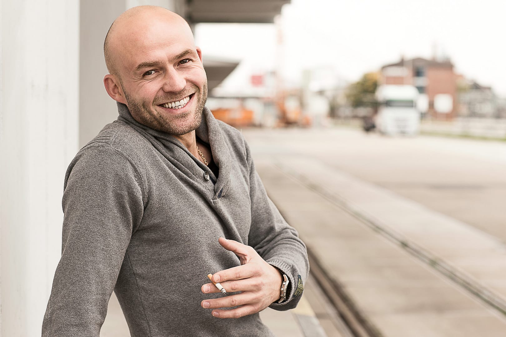 Outdoorportraitfoto eines Singlemannes mit Lächeln und Zigarette im Hafengebiet von Mannheim