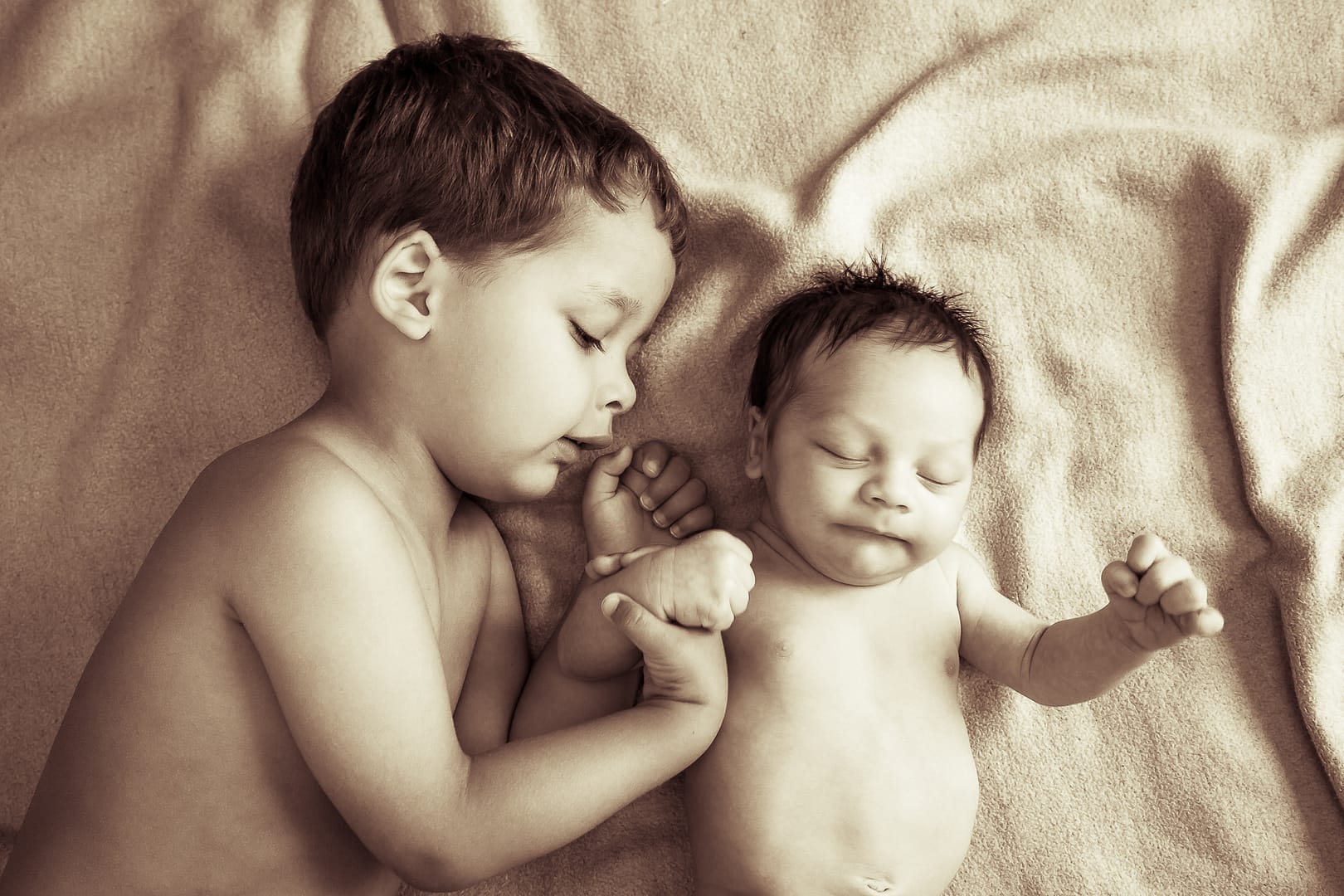 Kleinkind Baby liegend auf weichem Tuch mit Brüderchen. Bruder berühr das Baby. Schwarz-weiß-Foto