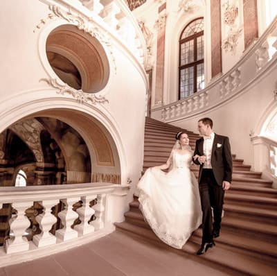 Brautpaar läuft die Treppe im Schloss hinunter