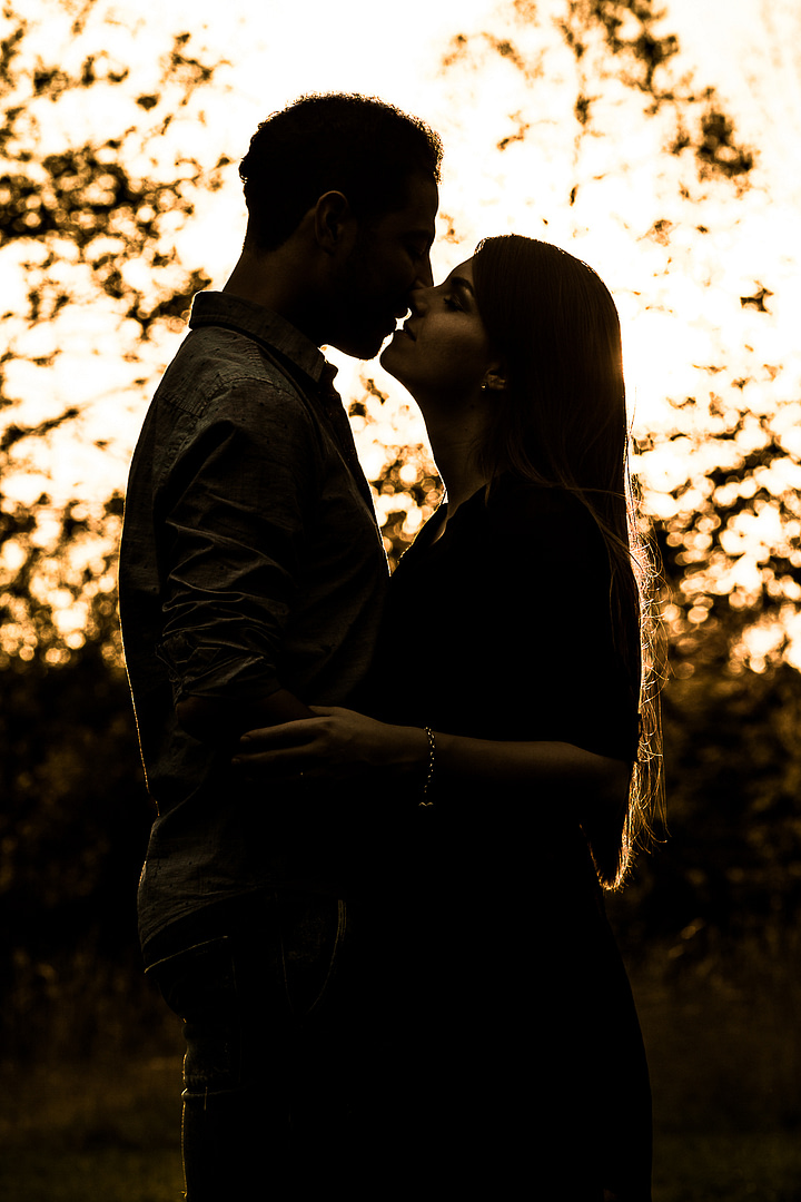 Die Silhouette eines jungen Liebespaares, während sie sich küssen und umarmen nach dem Sonnenuntergang. Nur das Gesicht des Mädchens ist leicht sichtbar.