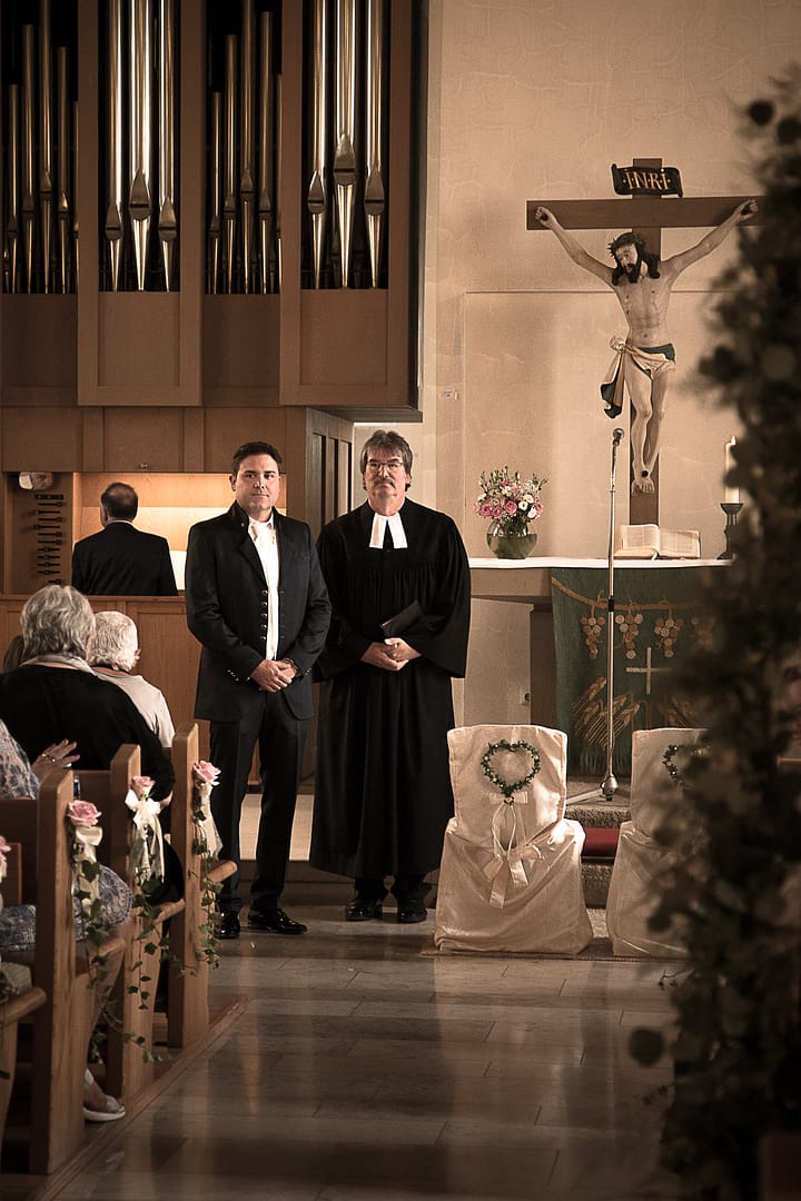 Der Bräutigam und der Priester stehen vor dem Altar und warten gespannt auf den Eintritt der Braut in den Kirchensaal.