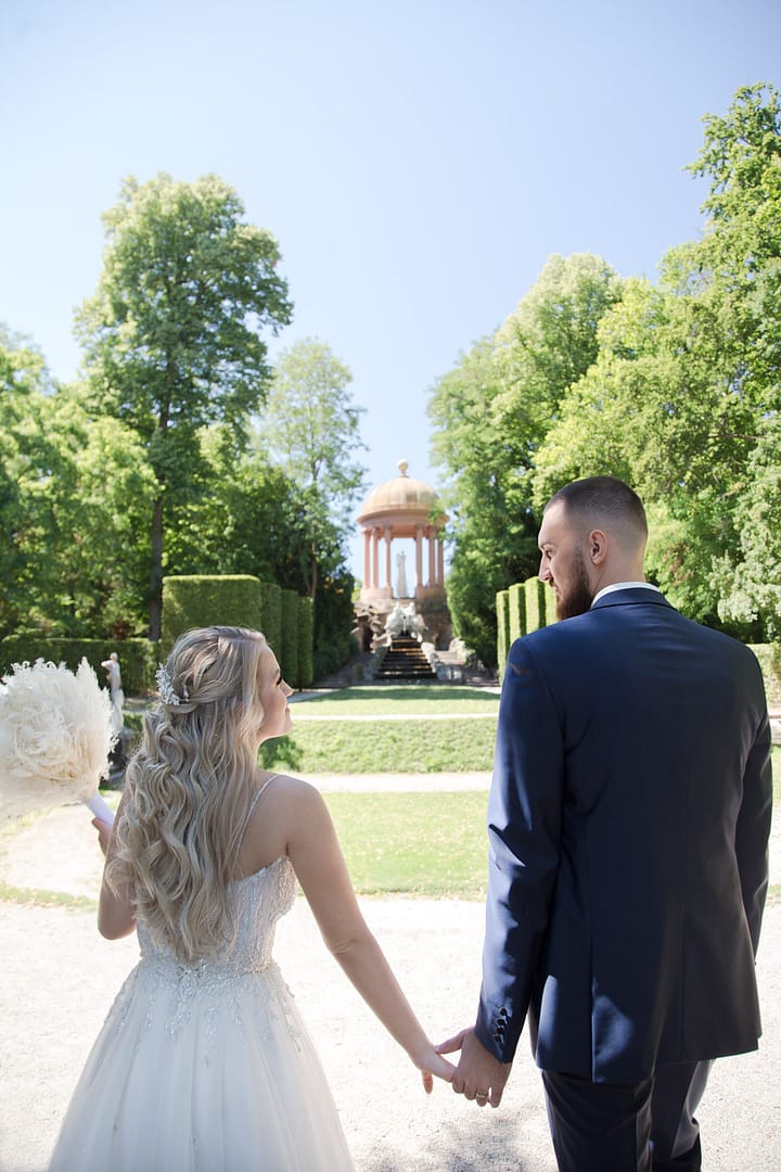 Braut und Bräutigam spazieren im Park mit schönem Blumenstrauß